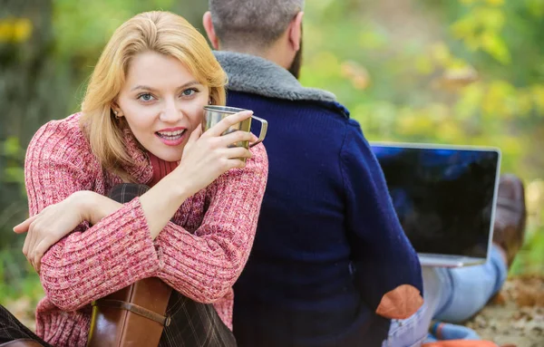 Work hard play hard. couple in love relax in autumn forest with laptop. happy girl drink hot coffee or wine. man sit with back. Spring mood. camping and hiking. Family picnic. Relationship