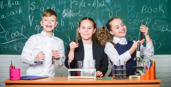 Los alumnos de la escuela grupal estudian líquidos químicos. Las niñas y los niños estudiantes realizan experimentos escolares con líquidos. Comprueba el resultado. Lección de química escolar. Tubos de ensayo con sustancias coloridas. Laboratorio escolar — Foto de Stock