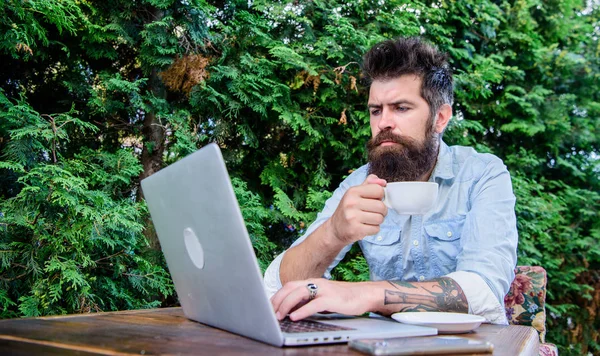 Arbeit und Spiel geben ihm Ruhe und Energie. bärtiger Mann bei seiner Arbeit im Internet. Hipster trinken Tee und nutzen Computerarbeitsplätze im Freien. Globales Arbeiten durch Fernarbeit — Stockfoto