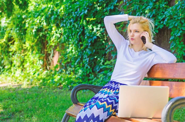 Woman with laptop works outdoors. Business woman works park with laptop smartphone. Girl smartphone call solve business problem. Technologies making life easier. Business lady solving problems remote