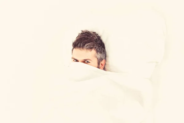 Guy hides face under blanket. Lazy and laziness