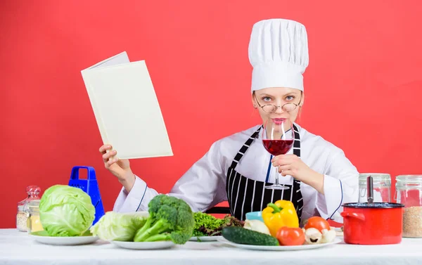 Trying a healthy dinner recipe. Pretty woman reading recipe book in kitchen. Housewife looking for cooking recipe in cookbook. Professional cook cooking vegetarian dinner according to recipe