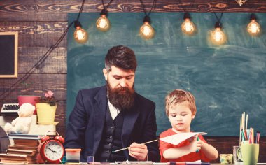 Öğretmen sakal, baba ve küçük oğul çizerken, sınıfta oluşturma, kara tahta arka plan ile. Sanat ders kavramı. Çocuk ve resim, çizim meşgul yüzleri öğretmen