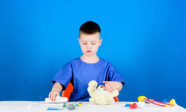 Koncepcja medycyny. Zabiegi medyczne na misia. Chłopiec Cute dziecko przyszłej kariery lekarza. Pracownik szpitala. Opieka zdrowotna. Kid mały lekarz zajęty siedzieć stół z narzędziami medycznymi. Lekarskie — Zdjęcie stockowe