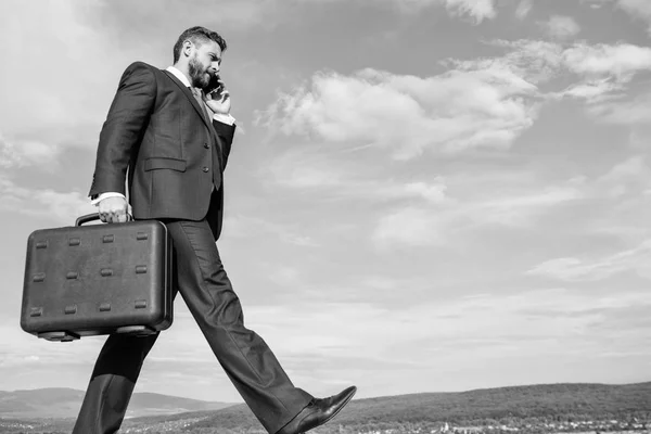 Keep going towards your goal. Businessman formal suit carries briefcase sky background. Businessman solving business problems on phone. Never stop. Entrepreneur in motion purposeful expression