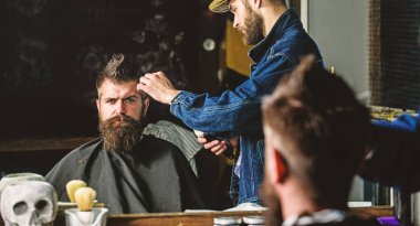 Hipster istemci Başlarken saç kesimi. Kuaför saç kesme makinesi ile saç modeli sakallı, berber arka plan için çalışır. Saç kesimi kavramı. Kuaför styling saç kesme makinesi ile acımasız sakallı istemci