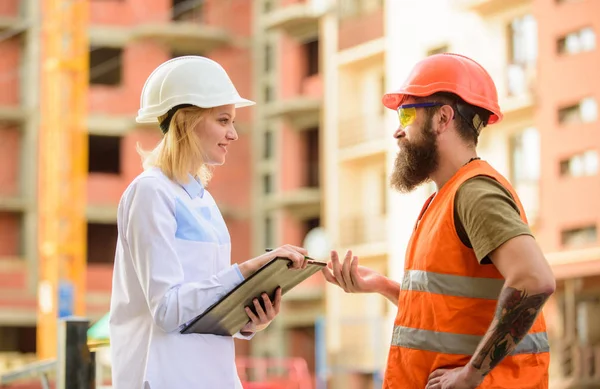 Inspecção de projectos de construção. Conceito de inspector de segurança. Inspetor mulher e construtor brutal barbudo discutir o progresso da construção. Inspeção de segurança do estaleiro. Discutir o projeto de progresso — Fotografia de Stock