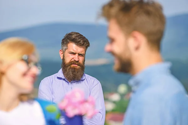 Amantes de la reunión al aire libre coquetear relaciones románticas. Pareja en el amor citas mientras marido celoso fijamente mirando en el fondo. Pareja romántica pareja amante presente flores ramo. Concepto de amor no correspondido — Foto de Stock