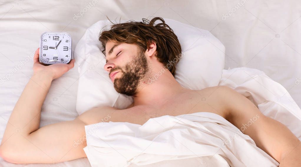 A young man waking up in bed and stretching his arms. Man feeling back ache in the bed after sleeping. Man on bed.