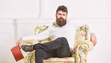 Koltuk, tutar kitap, beyaz duvar arka plan sakal ve bıyık oturur adam. Uzman düşünceli yüz kitap okumayı yeni bitirdim. Adam edebiyat hakkında düşünme. Uzman edebiyat kavramının