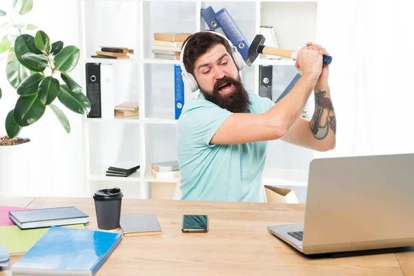 Slow internet connection. Outdated software. Computer lag. Reasons for computer lagging. How fix slow lagging system. Hate office routine. Man bearded guy headphones office swing hammer on computer