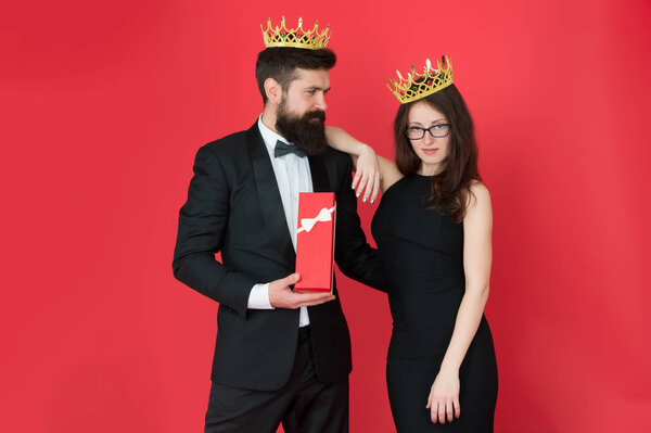 Royal gift. Queen of his heart. Man bearded king in tuxedo golden crown giving gift box to woman elegant dress. Royal family. Couple in love royal family. Elite society. King and queen formal event