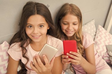 Pijama partisi konsepti. Kız kıza mutlu bir çocukluk. Akıllı telefonlu uzun saçlı kızlar modern teknoloji kullanır. Hadi selfie çekelim. Arkadaşlarının sosyal ağındaki fotoğrafını gönder. Çocuklar yatak odasında selfie çekiyor.