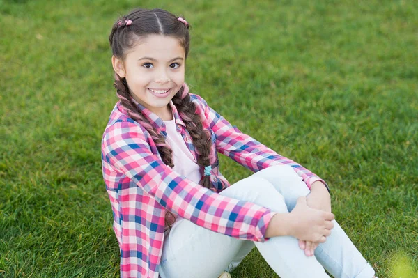 Vibras de verano. niña pequeña relajarse en la hierba verde. Parques y exteriores. Naturaleza de primavera. Picnic de verano. Niña de la escuela pequeña con el pelo de moda. Feliz infancia. parque con césped verde. sentado sobre hierba verde — Foto de Stock