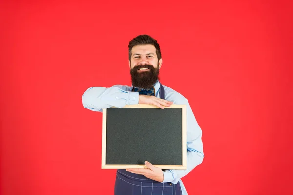 Assumere personale. Hipster barista mostra spazio di copia lavagna. Personale del ristorante hipster. Hipster ti sta informando. Uomo barbuto barista o cucinare in grembiule tenere lavagna bianca. Concetto di posti vacanti — Foto Stock