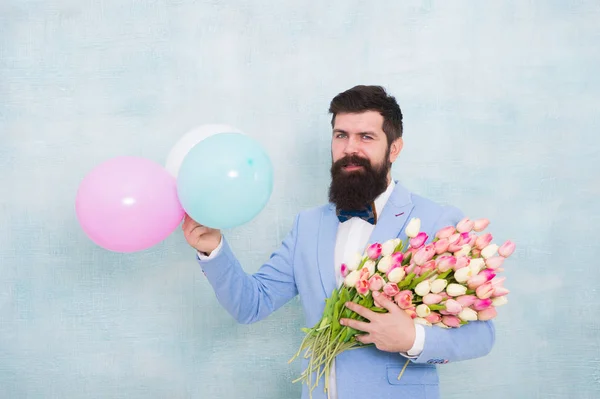 Für jemanden Besonderes. Der bärtige Herr im Anzug hält Luftballons und Blumensträuße in der Hand. Gentleman macht romantische Überraschung für sie. Blumenlieferung. Gentleman romantisches Date. Geburtstagsgrüße — Stockfoto