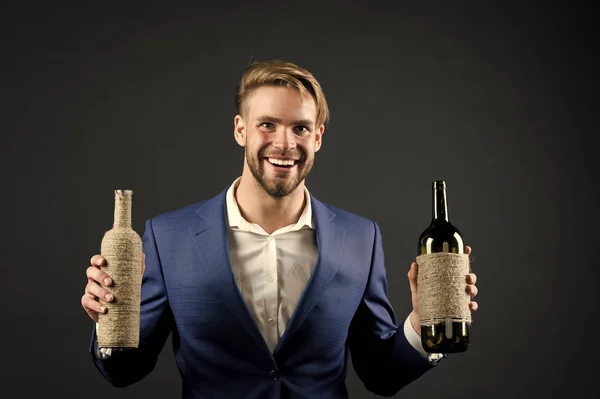 Sommelier rymmer två flaskor vin. Professionellt vin degustation koncept. Man formell kostym med vinflaskor i händerna. Sommelier stilig glad kille på mörk bakgrund. Vilket vin gillar du? — Stockfoto