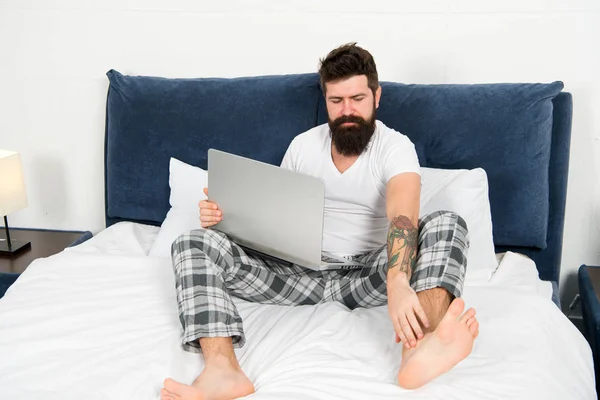 Man surfing internet or working online. Hipster bearded guy pajamas freelance worker. Remote work concept. Online life. Social networks internet addiction. Online shopping. Whole world in his laptop