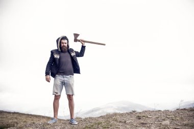 Adam acımasız sakallı hippi balta ile stand dağın tepesinde