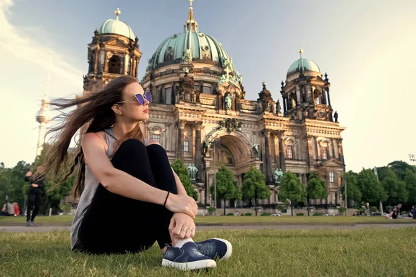 Unbekümmerte Mädchen entspannen in Deutschland am Berliner Dom. hübsche mädchen relaxen auf sommerrasen in der nähe des berliner doms in deutschland. Einfach nur entspannen. Momente der Freude. Keine Eile. Touristin mit langen windigen Haaren entspannen. — Stockfoto