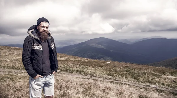 Hombre barbudo en la cima de la montaña ventosa en el cielo nublado natural —  Fotos de Stock