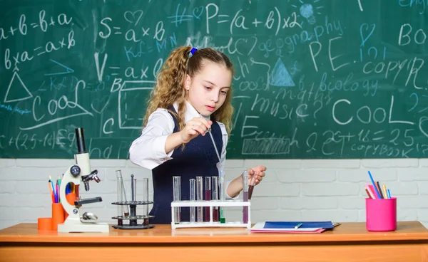 Experimentos de biología con microscopio. Niña. Ciencia. Ciencias químicas. Microscopio de laboratorio y tubos de ensayo. Una pequeña científica que gana química en el laboratorio escolar. Espera algo extra. — Foto de Stock