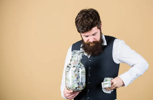 ポケットに現金を詰め込んだ現金を隠すあごひげの男ガラス瓶から現金を取り出すビジネスマン。キャッシュフロー予算、コピースペース — ストック写真