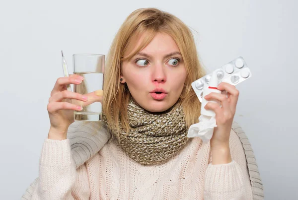 Tolerating the drug well. Ill woman treating symptoms caused by cold or flu. Unhealthy woman holding pills and water glass. Cute sick girl taking anti cold pill. Medication and increased fluid intake