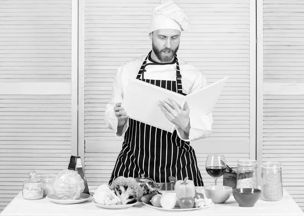 Hombre barbudo cocinero comida. El tipo leyó recetas de libros. Concepto de artes culinarias. Hombre aprender receta. Mejorar la habilidad de cocinar. Libro de recetas familiares. Guía de cocina definitiva para principiantes. Según la receta — Foto de Stock