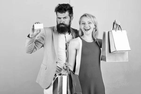 Couple with luxury bags in shopping mall. Couple enjoy shopping. Man bearded hipster hold credit card and girl enjoy shopping. Ask man to purchase lots presents for girlfriend. Paying while dating