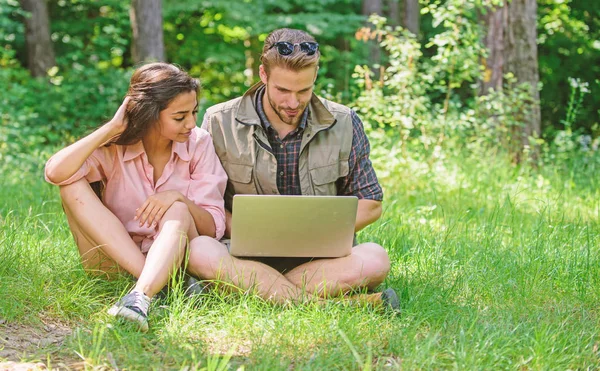 Couple youth spend leisure outdoors with laptop. Man and girl looking at laptop screen. Closer to nature. Modern technologies give opportunity to be online and work in any environment conditions