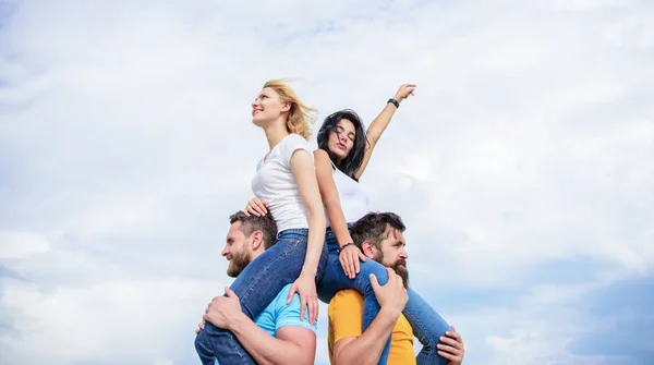 Enjoying life. Playful couples in love smiling on cloudy sky. Loving couples enjoy fun together. Loving couples having fun activities outdoor. Happy men piggybacking their girlfriends