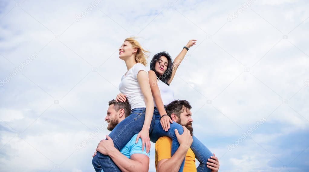 Enjoying life. Playful couples in love smiling on cloudy sky. Loving couples enjoy fun together. Loving couples having fun activities outdoor. Happy men piggybacking their girlfriends