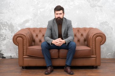 Şık ama sıradan. Sakallı adam kanepede dinleniyor. Gayri resmi takım giyen adam ya da iş adamı. Uzun sakallı ve modaya uygun saç stili olan moda adamı. Hipster yaşam tarzını takip eden zalim bir adam.