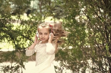 Küçük çocuk müzik kulaklık açık keyfini çıkarın. Çocuk dansçı ile uzun saç uçan. Melodi ses ve mp3. Kız dans müzik yaz Park. Yaz eğlence ve neşe