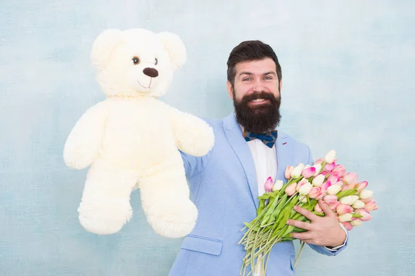 Sorpresa para ella. Caballero haciendo una sorpresa romántica para ella. Un regalo romántico para caballeros. Saludos de cumpleaños. Feliz cumpleaños, mi amor. Hombre barbudo caballero traje pajarita agarre osito de peluche y ramo —  Fotos de Stock