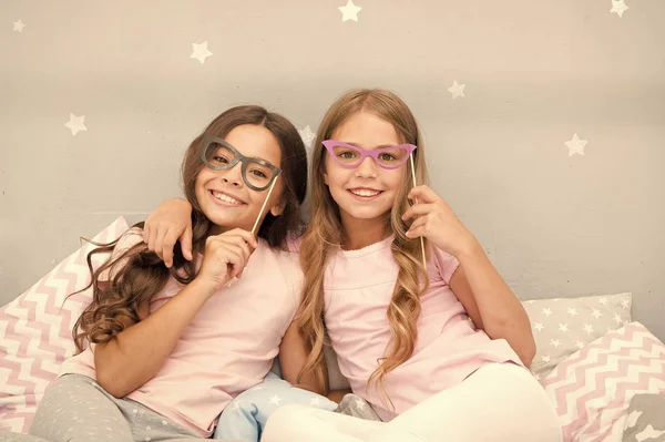 Compleanno. Bambini in posa con le smorfie foto cabina puntelli. Pigiama party in camera da letto. Amici carino e allegro in posa con gli occhiali accessori. Ragazze amiche divertirsi pigiama partito — Foto Stock