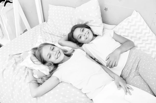 Pajama party and friendship. Sisters happy small kids relaxing in bedroom. Friendship of small girls. Leisure and fun. Having fun with best friend. Children playful cheerful mood having fun together — Stock Photo, Image