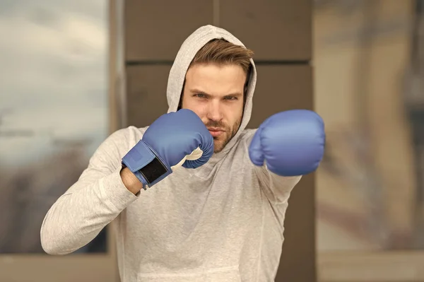 Fuerza y motivación. El deportista concentró los guantes de boxeo. Atleta cara concentrada con guantes deportivos practicar habilidades de lucha fondo urbano. Boxeador guapo estricto entrenador practicando —  Fotos de Stock