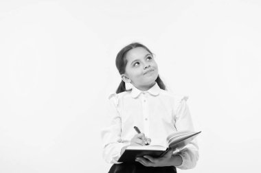 Okul üniformalı çocuk ödevlerini yapıyor. Çocuk okulu üniformaları kitap ve kalem tutuyor. Şirin kız fikir notları yaz. Hatırlanacak notlar. Kompozisyon ya da notlar yaz. Kişisel program. Not alıyorum.