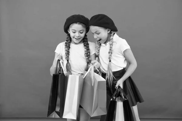 Kinderen genieten van winkelen rode achtergrond. Een bezoek aan kleding mall. Korting en verkoop concept. Kinderen leuke meisjes houden boodschappentassen. Winkelen korting seizoen. Speciale aanbieding. Geweldige dag om te winkelen — Stockfoto