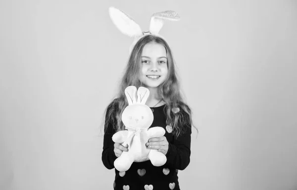 Der Hase ist ein Symbol für Fruchtbarkeit und Frühling. Kleine Kinder bekommen am Ostertag ein Hasengeschenk. kleines Mädchen mit Osterhasenspielzeug. fröhliches Kind spielt mit süßem Osterhasen — Stockfoto