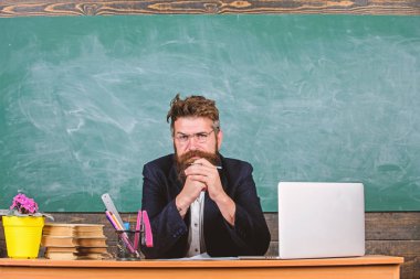 Öğretmen Olgun öğretmen dikkatle dinlerken sakallı. Öğretmen formal giyim oturup tablo sınıf kara tahta arka plan. Öğretmen dinleme cevap veya rapor. Ayrıntılara dikkat