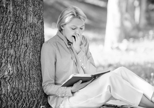 Relax Freizeit und Hobby Konzept. Die besten Selbsthilfebücher für Frauen. Mädchen müde gähnend sitzen Park mageren Baumstamm lesen Buch. Lesen inspirierender Bücher. Bestsellerliste. Bücher, die jedes Mädchen lesen sollte — Stockfoto