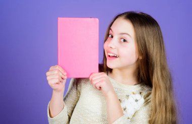 Ek bilgi. Küçük kız hayati bilgiler için pembe kapaklı kitap gösteriyor. Bilgi materyalleri olan küçük bir çocuk. Bilgi ve eğitim, kopyalama alanı