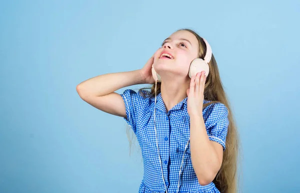 Inspirado pela música. Miúdo a ouvir música. Miúdo bonito com fones de ouvido fundo azul. Menina pequena usando fones de ouvido estéreo. Criança usando tecnologia para lazer ou educação. Headphones modernos — Fotografia de Stock