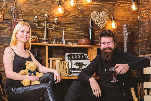 Casal passar a noite romântica em casa gamekeepers, fundo interior de madeira. Casal apaixonado por ursinho de pelúcia e vinho quente. Menina e homem em rostos felizes relaxar em ambiente acolhedor. Conceito relaxante — Fotografia de Stock