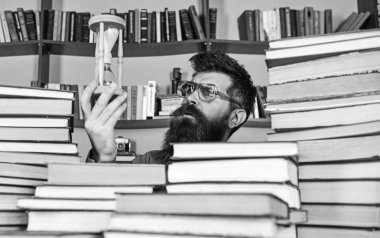 Adam düşünceli yüzünde ise eğitim, kitap rafı arka plan üzerinde kum saati tutar. Dostum, bilim adamı bardaklarda kum saati görünüyor. Zaman akışı kavramı. Öğretmen ya da sakal Kitaplığı'nda eğitim ile öğrenci