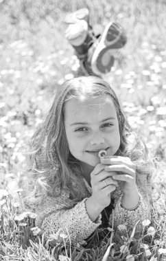 Duyarlılık kavramı. Yüz gülümseyerek kıza papatya çiçek tutan, aroma burnunu çekmek. Çimen, grassplot arka plan üzerinde yatan kız. Çocuk zevk bahar güneşli havalarda çayır papatya çiçekleri ile yalan süre