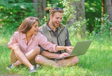 Modern teknolojileri online ve herhangi bir çevre koşulları çalışmalarına olmak için fırsat verir. Serbest fırsat. Adam ve kız dizüstü bilgisayar ekranına bakarak. Çift gençlik eğlence dizüstü bilgisayar ile açık havada harcamak